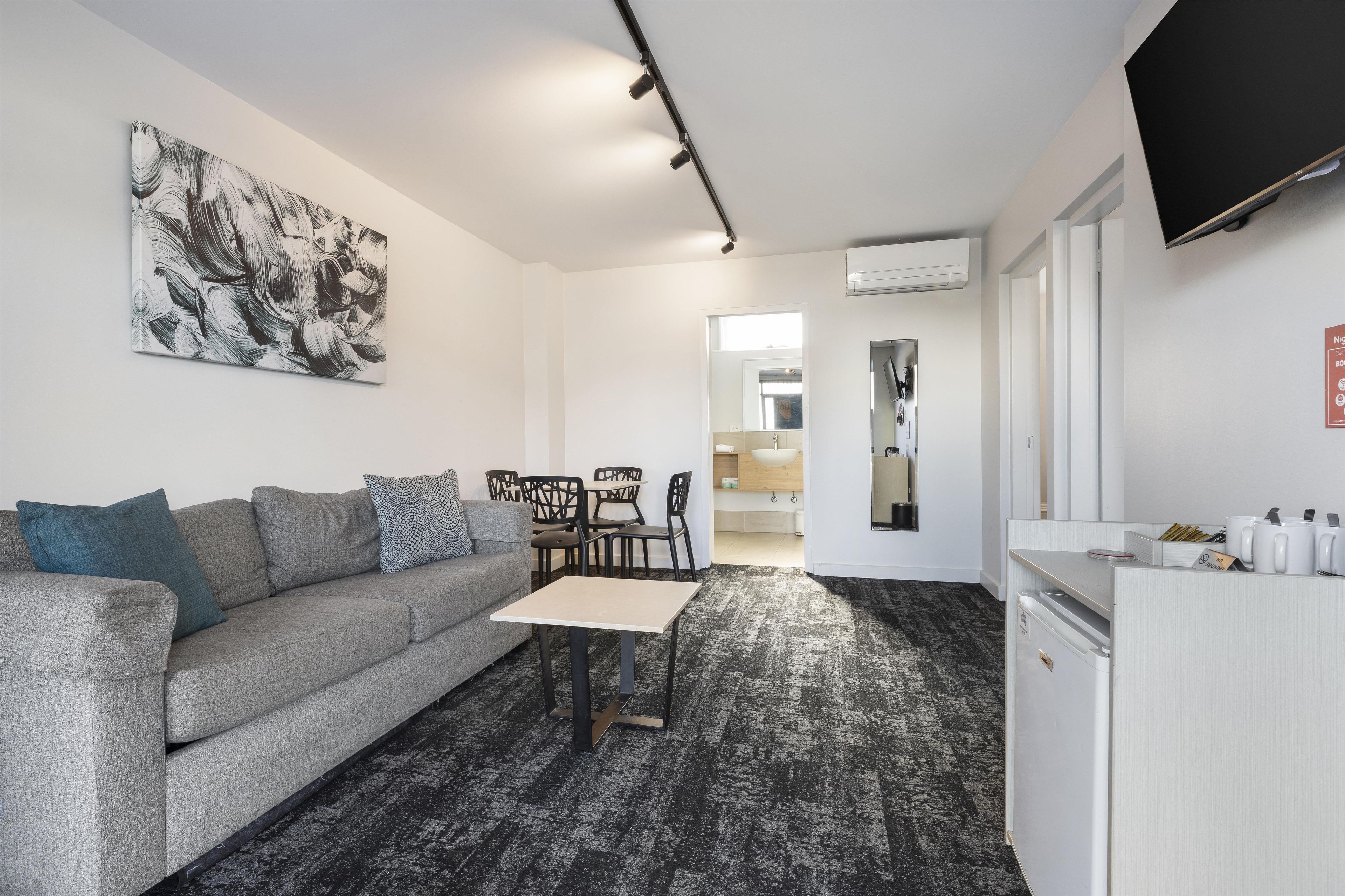 A modern living room with a grey sofa, a coffee table, and a black and white abstract painting on the wall.