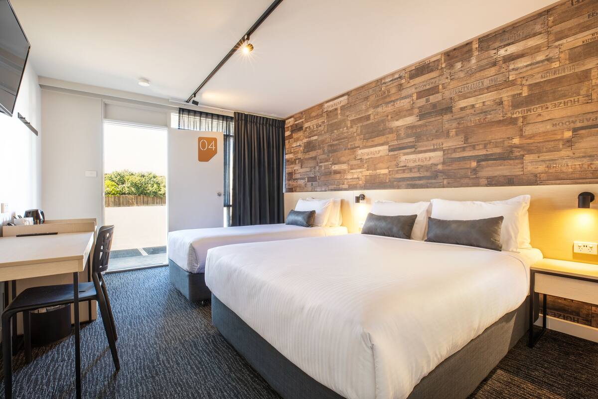 A modern hotel room with a large bed, a desk, and a chair.