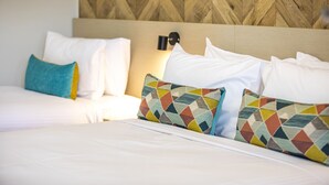 Una habitación de hotel con cama, almohadas y cabecero con diseño geométrico.