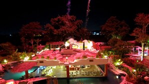 A nighttime view of a resort with a pool area, lounge chairs, and a covered seating area. - Mirabel Resort & Mini Golf (Pattaya)