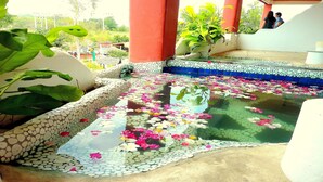 A water feature with a stone border and floating flowers. - Mirabel Resort & Mini Golf (Pattaya)