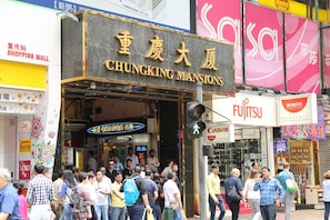 Una calle concurrida con un cartel llamativo que dice 'CHUNGKING MANSIONS'.