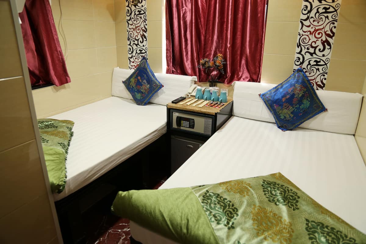 A hotel room with two single beds, a small table with toiletries, and a decorative pillow.