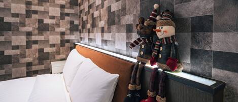 A hotel room with a bed, a headboard, a wall with a checkered pattern, and a plush toy hanging on the headboard.