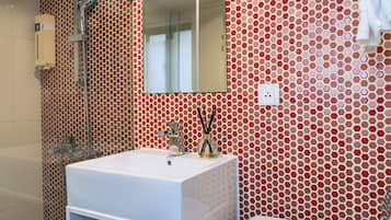 Un baño con lavamanos blanco, espejo y retrete.