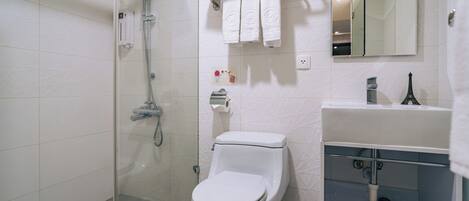 Une salle de bain moderne équipée de toilettes, d’une douche, d’un lavabo et d’un miroir.