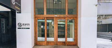 A hotel entrance with a double door, a signboard, and a tiled floor.