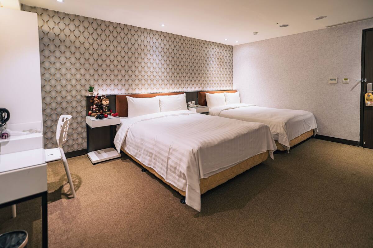 Habitación de hotel con dos camas, un escritorio y una pared con diseño.