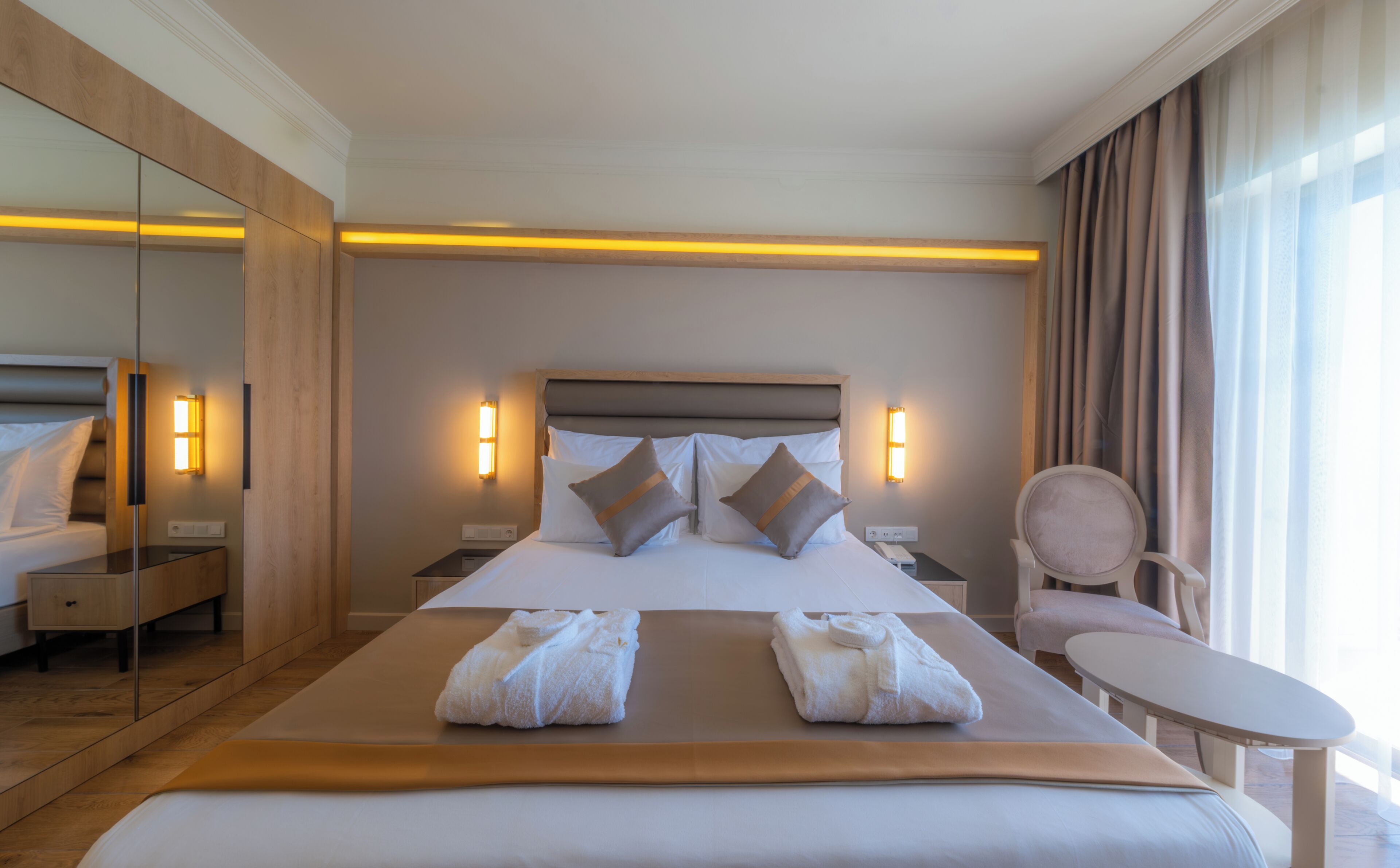 Ett hotellrum med en stor säng, sänglampor, en stol och en spegel.