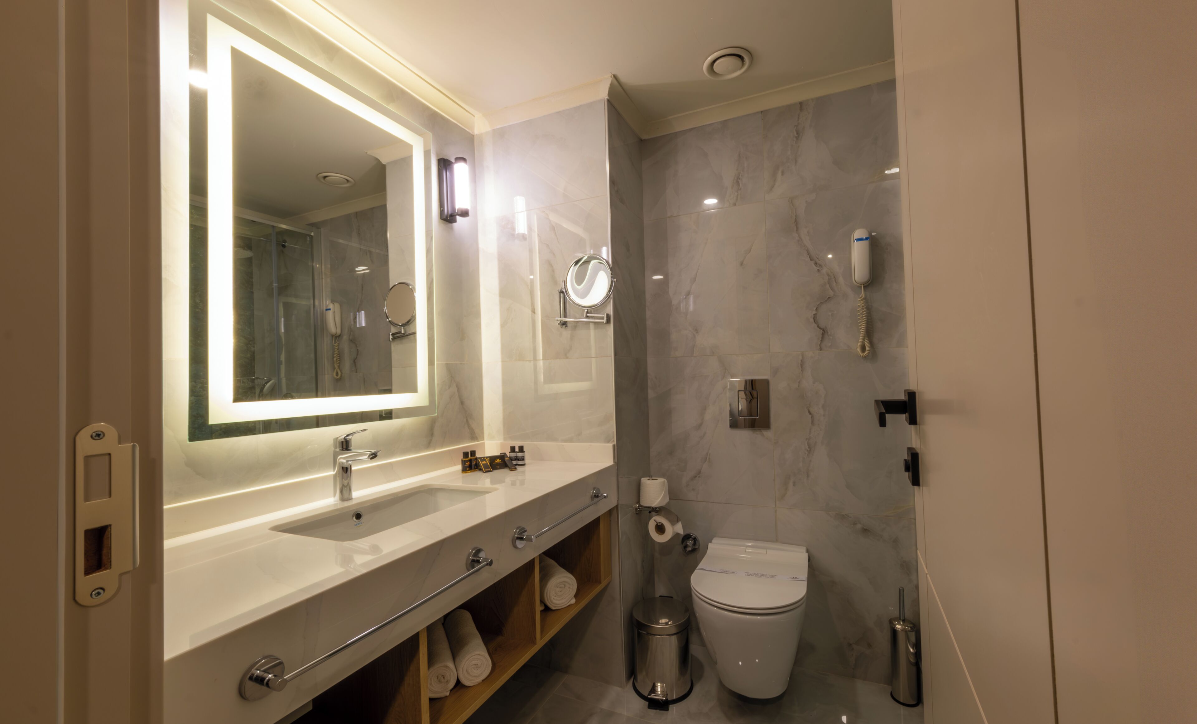Un baño moderno con un espejo grande, un lavabo, un inodoro y una zona de ducha.