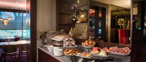 A buffet with various food items and a seating area with chairs and a table.