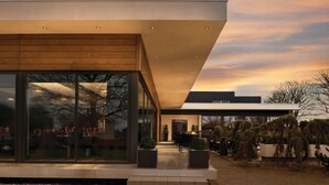 A modern building with large glass windows, a flat roof, and a well-lit entrance.