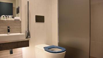 A modern bathroom with a white sink, a blue toilet, and a glass shower enclosure.