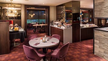 A modern dining area with round tables, purple chairs, and a bar counter.