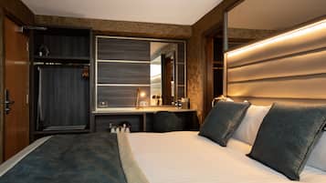 Quarto de hotel com uma cama grande, uma secretária com espelho e um guarda-roupa.