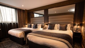 A hotel room with two beds, a large mirror, and a carpeted floor.