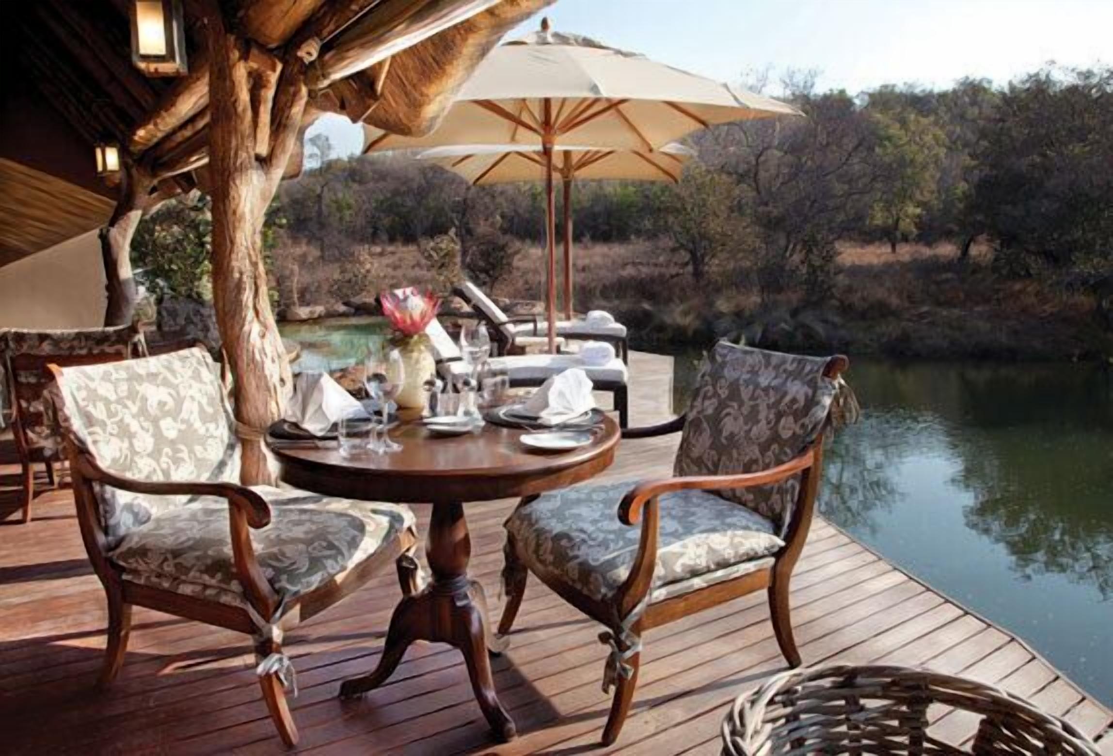 An outdoor dining area with two chairs, a table, and a large umbrella.