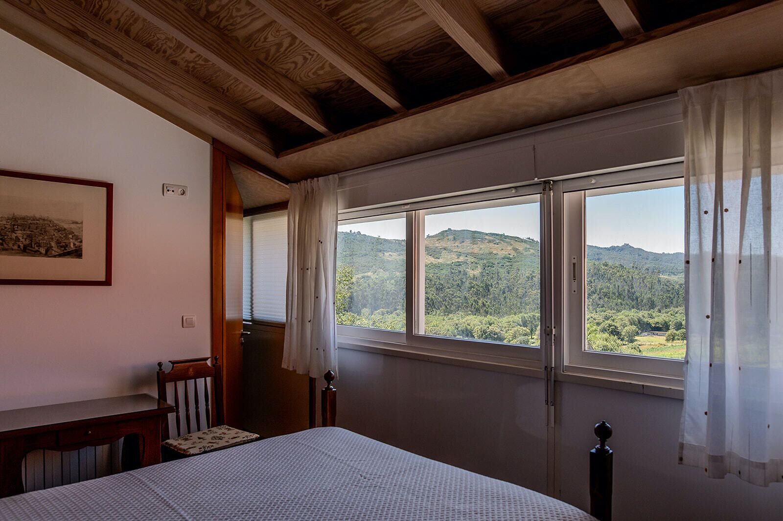 Un dormitorio con un ventanal que ofrece vistas a una ladera boscosa.