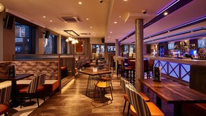 A restaurant with booths and tables, a bar area, and a view of the street. - The Royal Hotel (Cumnock)