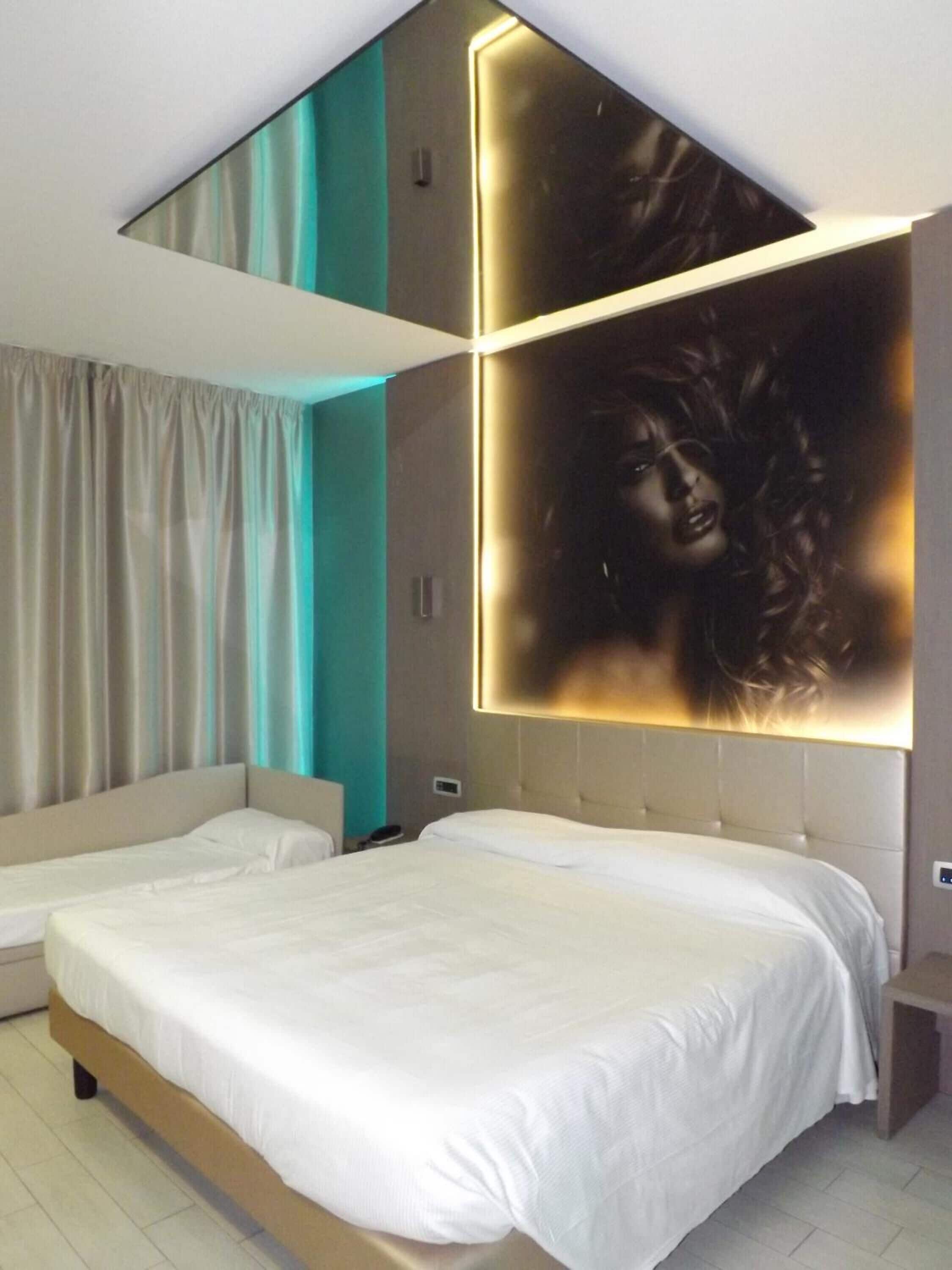 A modern bedroom with a large bed, a bedside table, and a wall-mounted light fixture.