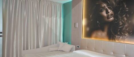 A modern hotel room with a large bed, a view of the city, and a large window with curtains.