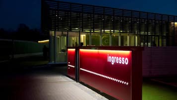 A modern building with a prominent red entrance sign reading "ingresso".