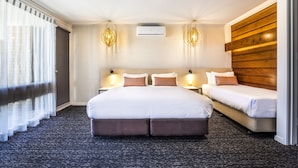 A hotel room with a large bed, a smaller bed, two bedside tables, an air conditioning unit, and a wooden accent wall. - Nightcap at Gateway Hotel (Corio)