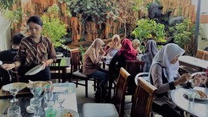 Un restaurante con terraza, decoración de madera y plantas.