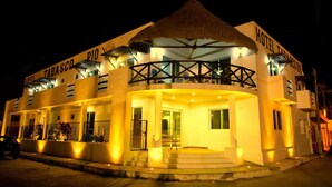 Hotel amb teulada de palla, un balcó i entrada ben il·luminada.