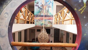 Un interior de diversos nivells amb un espai central obert, una làmpada esfèrica penjant i un mural a la paret superior.