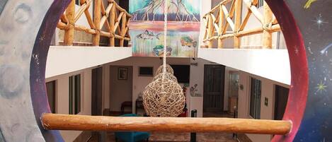 A multi-level interior with a central open space, a hanging spherical light fixture, and a mural on the upper wall.