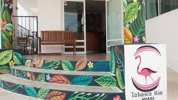 La entrada al Hotel Tabasco Rio, con un banco de madera y escalones coloridos que conducen a la puerta.