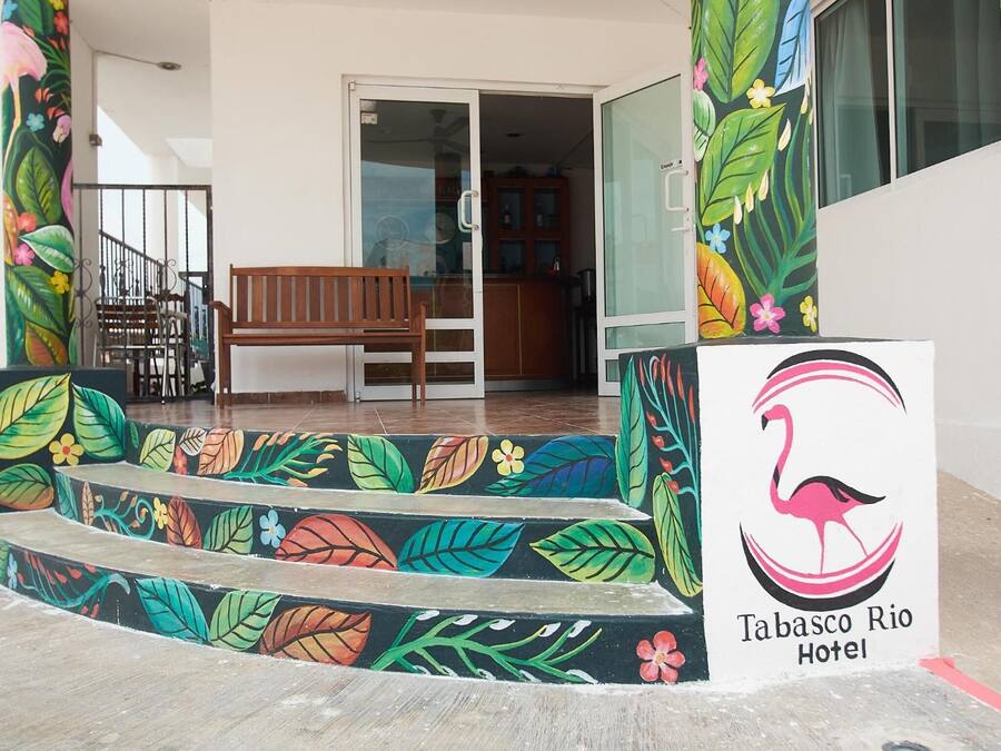 La entrada al Hotel Tabasco Rio, con un banco de madera y escalones coloridos que conducen a la puerta.