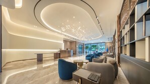 A modern lobby with a reception desk, seating area, and a large window offering a view of the outdoors. - The Legacy Hotel (Nonthaburi)
