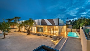 A modern building with a pool, surrounded by trees and a clear sky. - The Legacy Hotel (Nonthaburi)