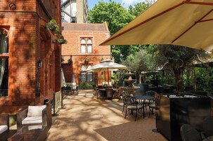 An outdoor patio area with brick walls, outdoor seating, and umbrellas.