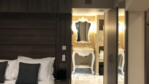 Une chambre d’hôtel avec un grand lit, une coiffeuse avec un miroir et un dressing.