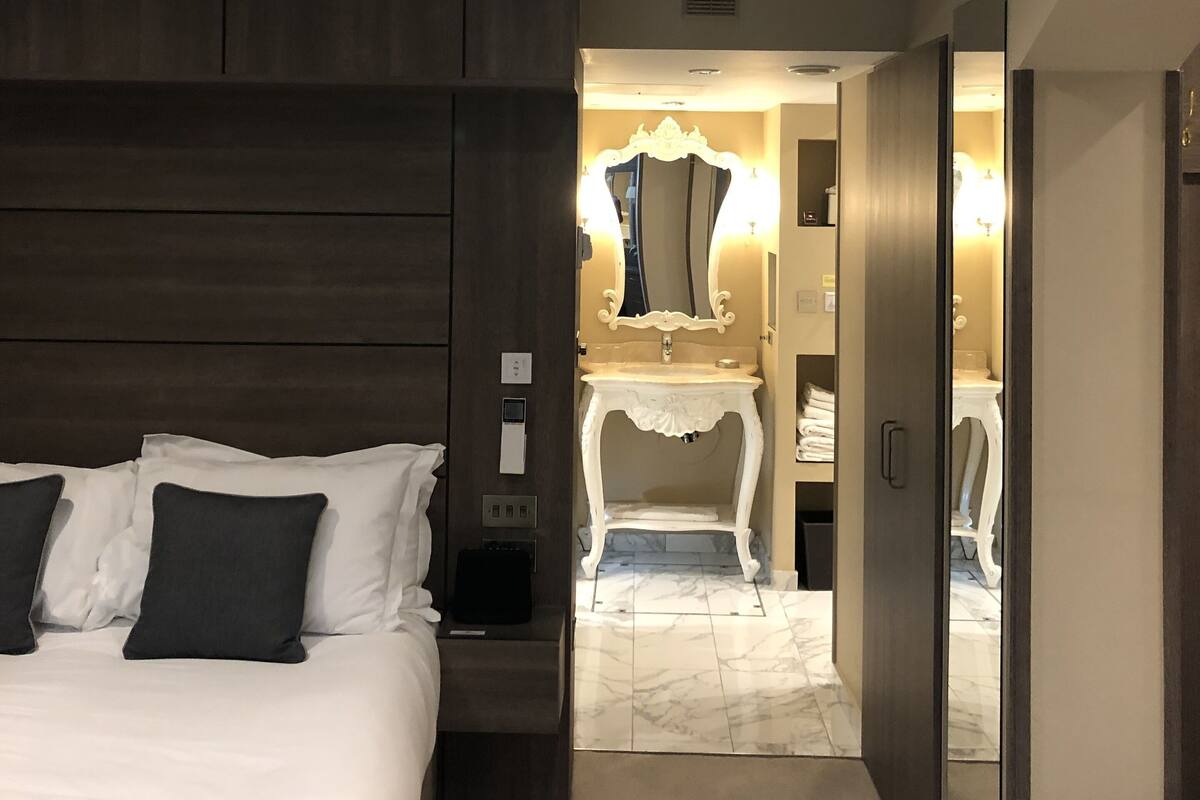 A hotel room with a large bed, a vanity with a mirror, and a walk-in closet.