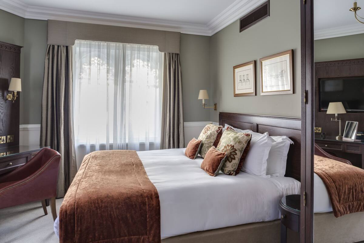 A hotel room with a large bed, a desk, and a chair.
