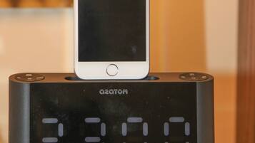 A digital clock with a white iPhone placed on top.