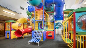 A colorful indoor play area with slides, tunnels, and play structures.
