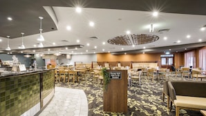 A hotel lobby with a reception area, seating arrangements, and a sign indicating a waiting area.