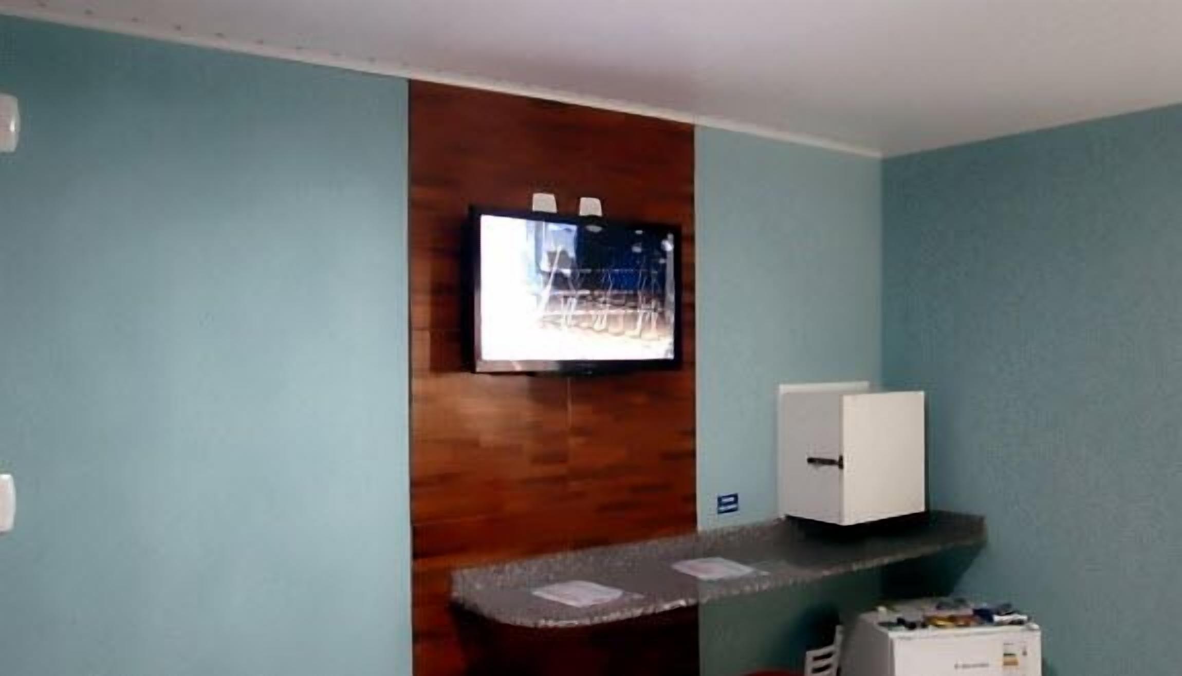 Ein Empfangsbereich mit einer Wand als Holzdekor, einem flachbildschirm-Fernseher über einer Theke und einem weißen Schrank zur Rechten.