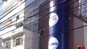 A building with a sign that reads "ESTAMOS FUNCIONANDO" and a large circular logo with "ATLANTA" on it. - Hotel Atlanta (Salvador)
