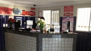 A reception desk with a tiled counter, a computer, and a vase with flowers. - Hotel Atlanta (Salvador)
