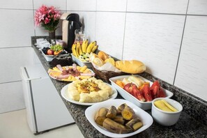 A buffet table with various food items including fruits, vegetables, and bread. - Hotel Atlanta (Salvador)