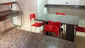 A kitchen with a granite countertop, red chairs, and a stainless steel stove. - Hotel Atlanta (Salvador)