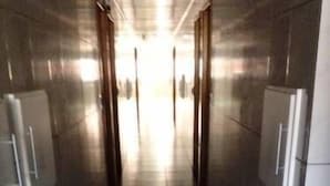 A corridor with tiled walls and floor, leading to a bright area at the end. - Hotel Atlanta (Salvador)