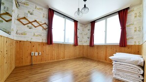 Ein Zimmer mit Holzwandverkleidung, großen Fenstern mit roten Vorhängen und einem Stapel weißer Kissen.