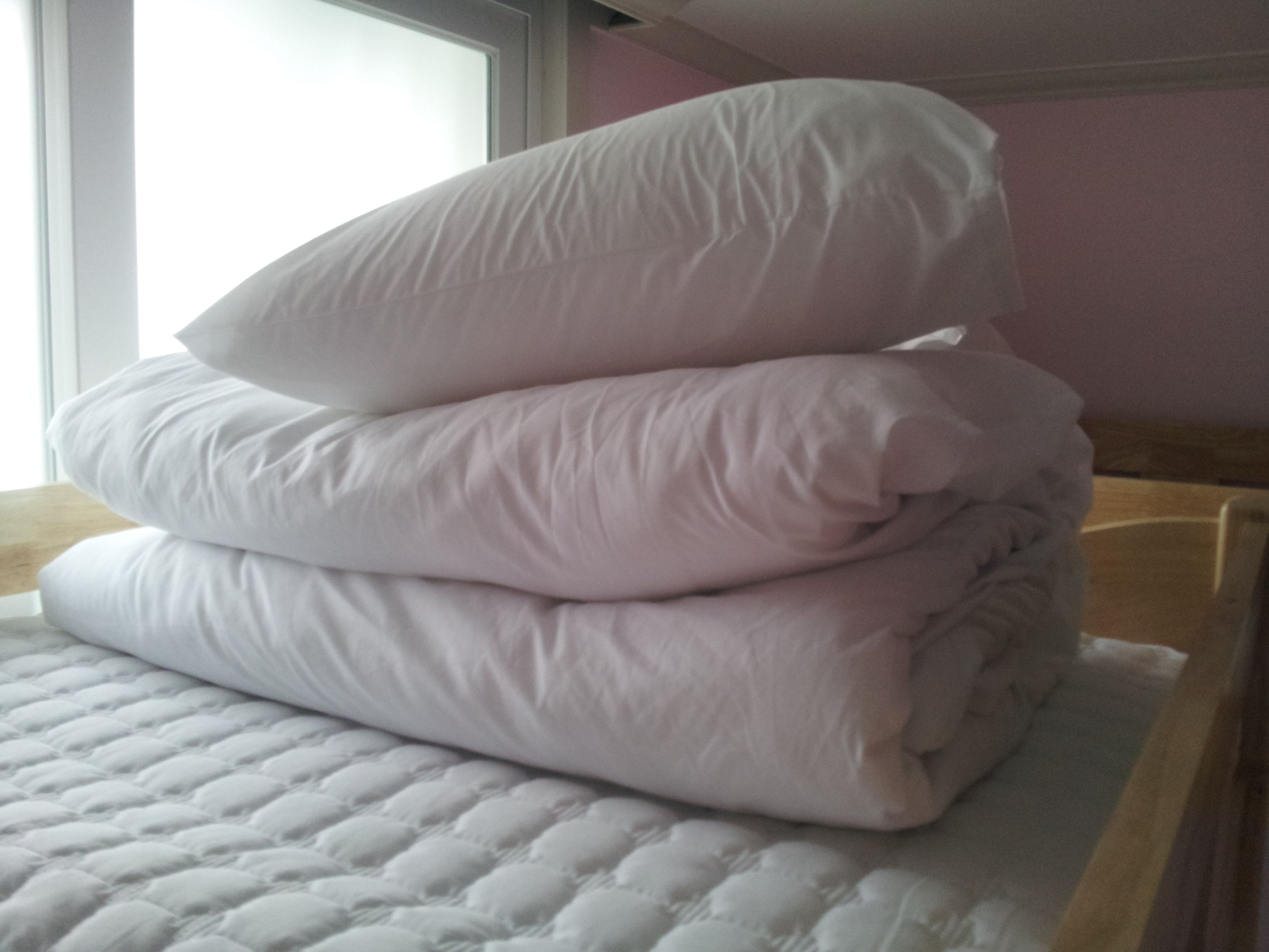 A stack of white pillows on a bed with a quilted cover.